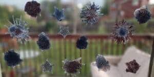 Picture of 4th of July window clings in the shapes of stars and fireworks made with red silver and blue glitter hanging up on a back door.