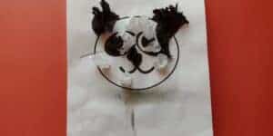Picture of a 3d textured tissue paper panda craft made by a preschooler. There are only a few pieces of tissue paper glued to a picture of a panda and arms and legs are drawn on with pencil