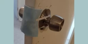 Picture of a blue piece of felt attached using elastic to doorknobs as a door latch cover