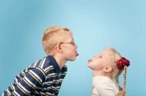 Teenage boy and girl stick out tongues to each other