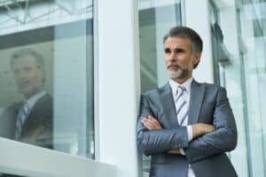 medium-shot-businessman-standing-with-arms-folded-leaning-window-frame