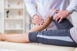 Physical therapist measuring knee range of motion with goniometer