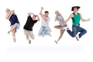 Group of young teenagers jumping over white