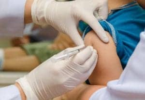 Doctor give injection of vaccine to boy's arm