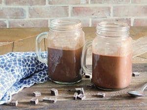 red wine hot chocolate in mugs on wooden table with blue napkin