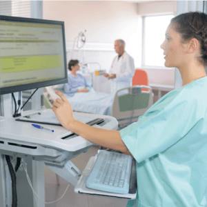 A nurse uses health information technology while a doctor and patient discuss benefits in the background