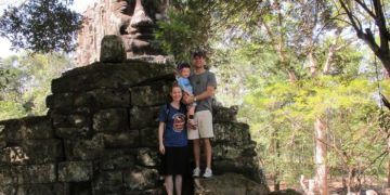 The family at the north gate of angkor wat, siem reap's most famous ruined temple.