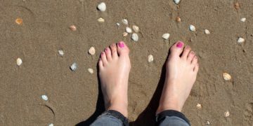 Feet on a beach with pink toenails
