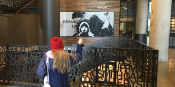 A girl checks out her pixelated image that moves with her at landmark near fenway park, boston