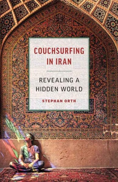 The author of couhsurfing in iran sitting in front of an elaborate persiab mural.