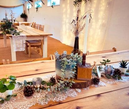 Artificial potted plants, copper and wood candle holders, brown bottles with grasses, artificial mini-succulents, log slices