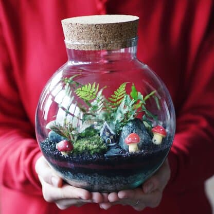 świąteczny las w słoiku dla dzieci trzymany w dłoniach