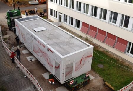 Zentimetergenau stellt der Schwerlasttransporter den 30 Tonnen schweren Container ab. Der Standort liegt dicht bei der Radiologischen Abteilung.
