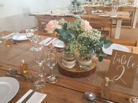 Log slices for table centrepieces with mix and match jam jar vases decorated with hessian and lace