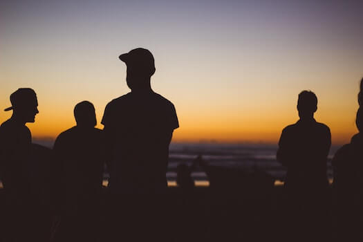 Silhouettes of Young People with Sun Setting in the Distance