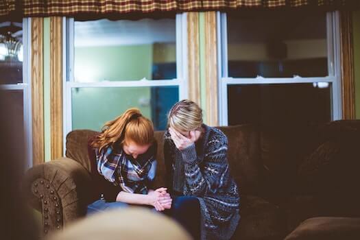 Two Women on Couch Upset with Head in Hands