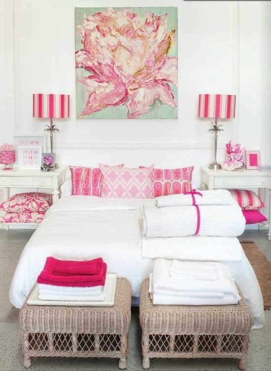 a big painting of a pink flower complements a white and pink bedroom perfectly