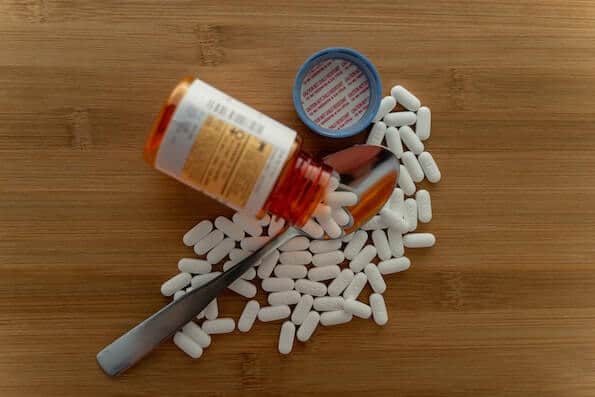 Open prescription opioid pill bottle and spoon