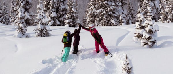 A ski instructor in whistler high fives two teens