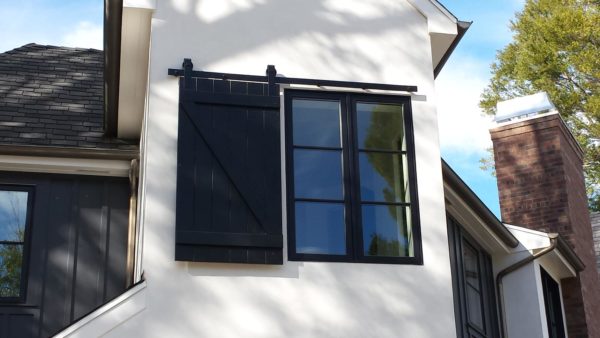 simple black barn door window shutters against white exterior in a modern home