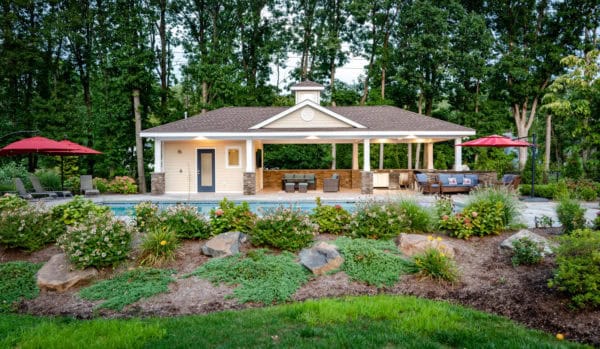 beach style pool surrounded with verdant greeneries and an open-air pool house with bathroom