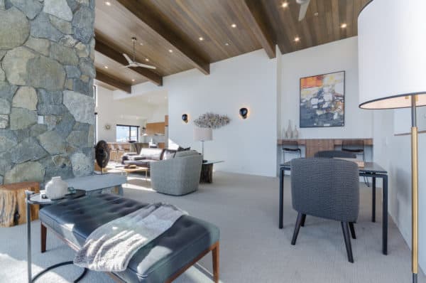 a formal white and gray living room mixes stone wall and wood ceilings for a minimalist yet natural vibe