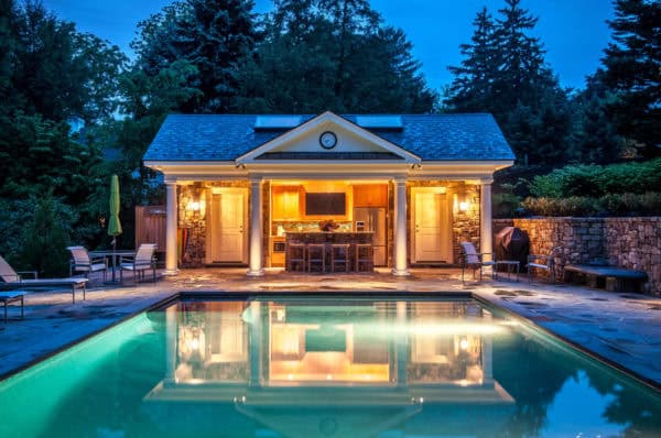 dramatic pool house in greek style with a hidden bathroom behind an exquisite pool