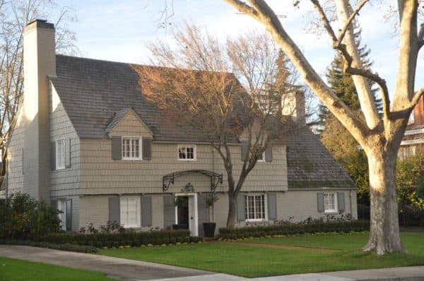 a gorgeous house with grey shutters, brown siding, and old-school ironwork decor