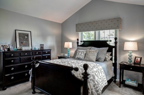 evoke the classic cottage house coziness in this grey bedroom with traditional black furniture