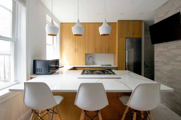 this modern, 1960s inspired small kitchen with a peninsula features wood cabinets and quartzite countertops