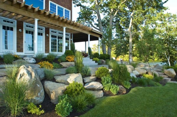 try a luscious front yard featuring landscaping slopes with rocks and ornamental grasses