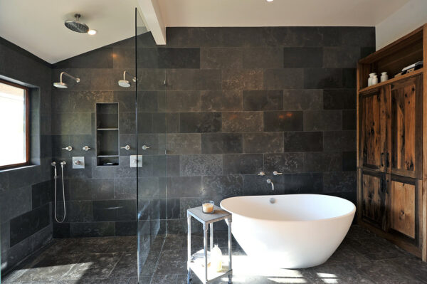 create a rustic dark grey bathroom with charcoal limestone tiles and a country wood cabinet