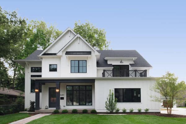 a small cozy white siding house with modern-look black windows as the accent