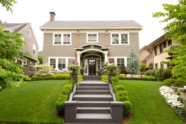 dark brown front door complements beveled beige siding in a colonial-style house