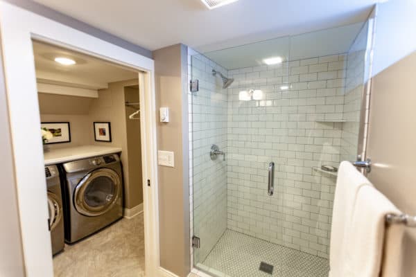 build a mini laundry room connected to the bathroom with beige walls and tiled shower