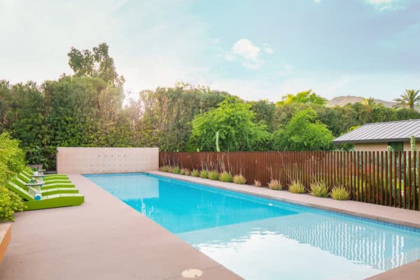 round off your stamped concrete pool deck with horizontal wood fencing and green sunbeds