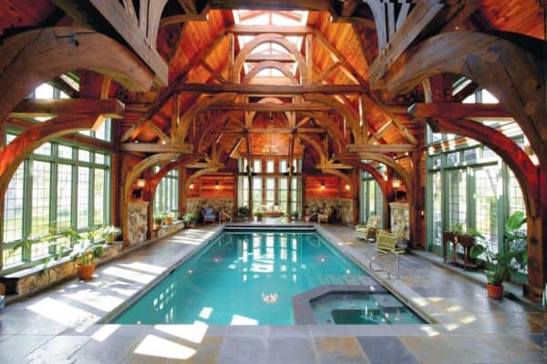 rustic indoor pool featuring stamped concrete deck and opulent vaulted ceilings