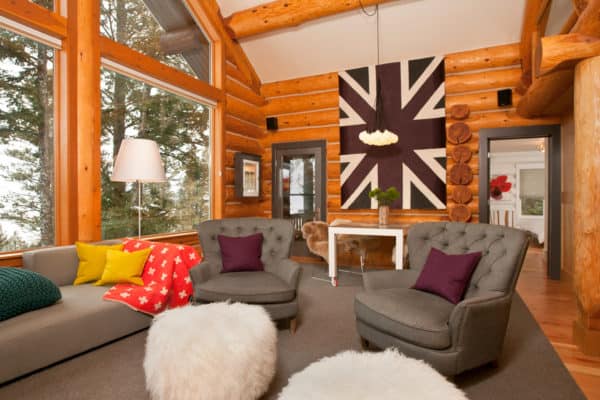 trendy log cabin living room features contemporary wall art and champagne armchairs