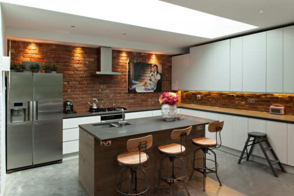 install real brick walls and place brown island for a chic and eclectic white kitchen