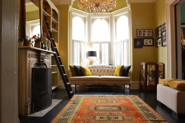 create an eclectic nook in a living room with a bay window through rustic carpet and traditional chandelier