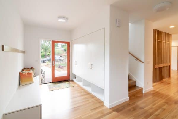 an orange front door with a large glass panel can look super modern with a bright white interior