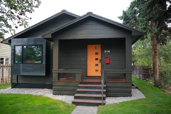 choose contrasting orange color for the front door against dark grey walls and brown floors