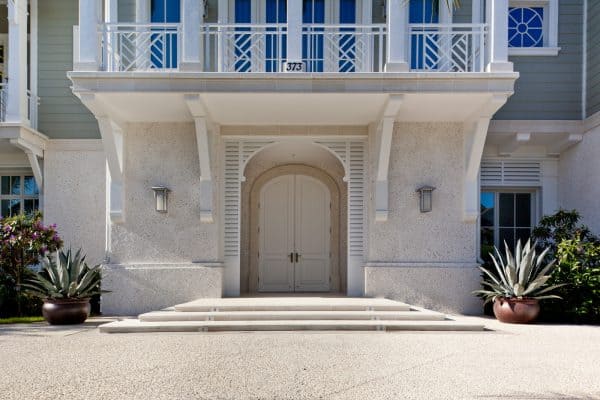 embrace an island-styled entryway with a stunning, arched white front door