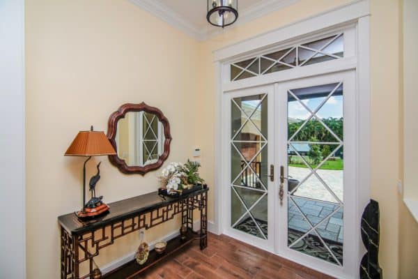 this white pgt double front door complements the porcelain tile entryway and wood floor interior