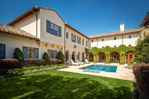 this mediterranean yellow house features a gorgeous courtyard with blue shutters and wood frames