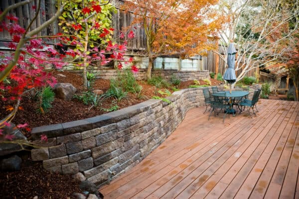 embrace rustic landscaping with a rugged fence on allan block’s europa retaining wall