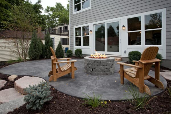 place wooden adirondack chairs on a stamped concrete patio with a fire pit for a traditional and timeless appeal