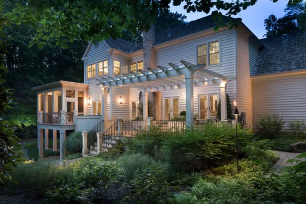 this stunning luxury deck has a front door pergola for shade and alluring warm lighting