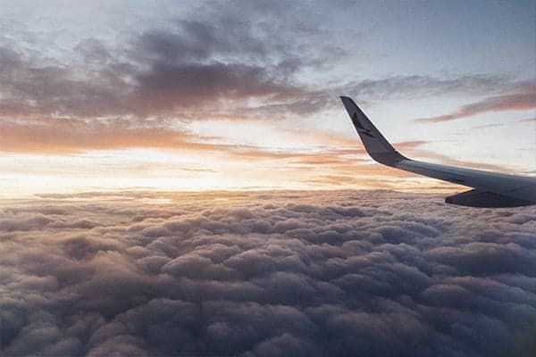 The wing of an aeroplane in the clouds at sunset