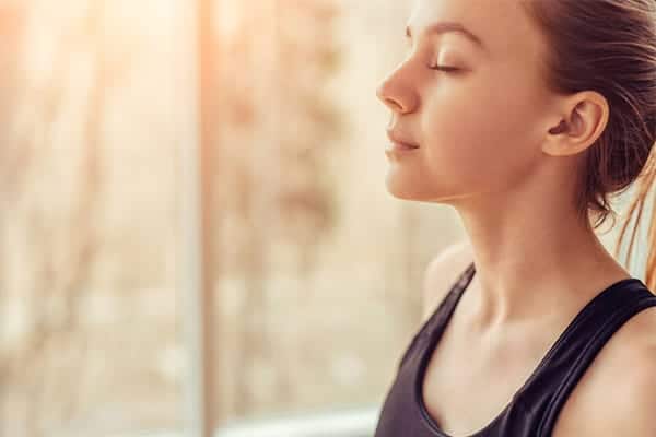 Close up of lady with eyes closed while meditating to overcome the January blues.